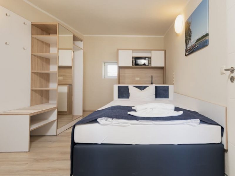 Sleeping area with bed and closet in the Studio-S accommodation at Aparthotel Stralsund