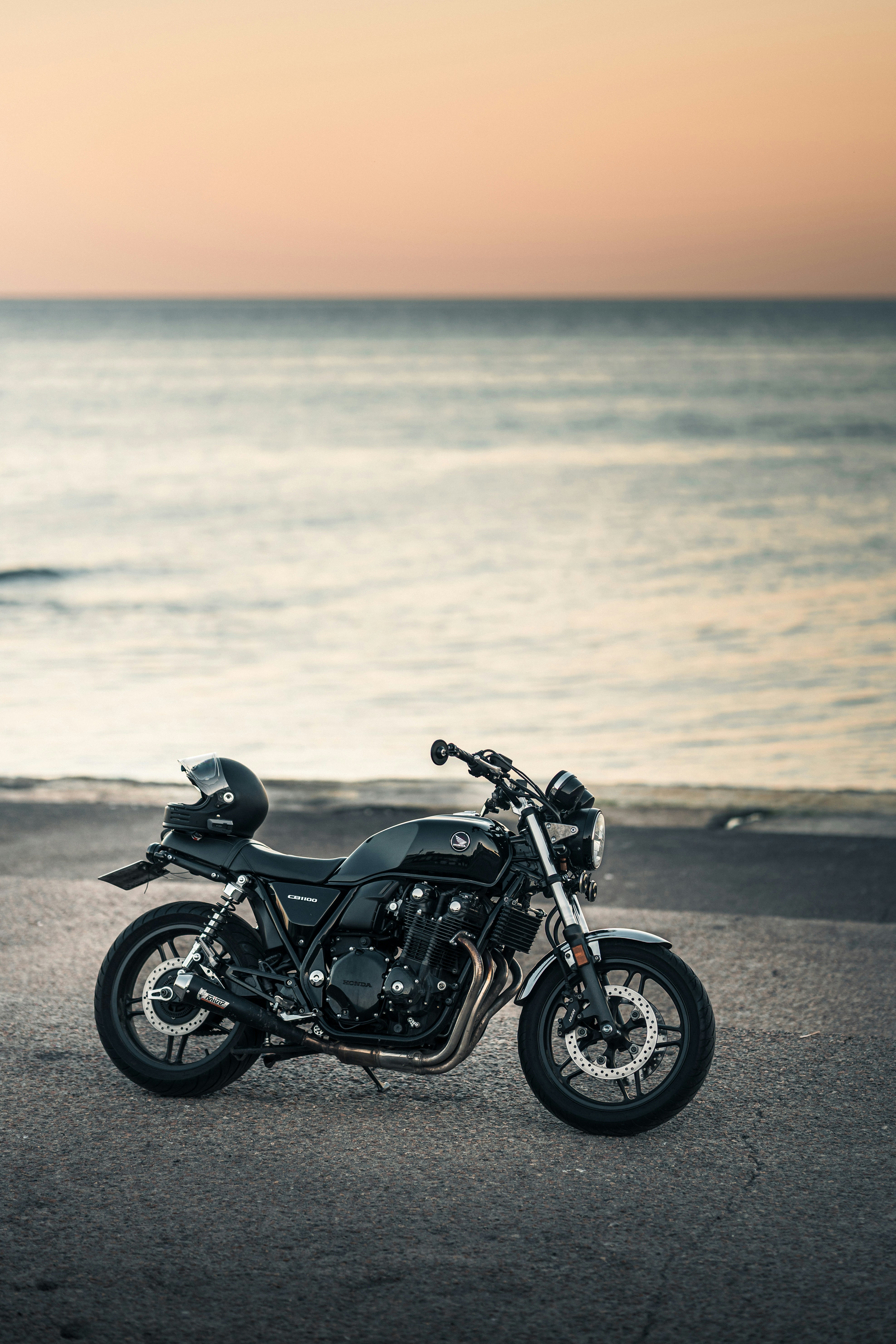 Klassisches Motorrad am Meer im Sonnenuntergang